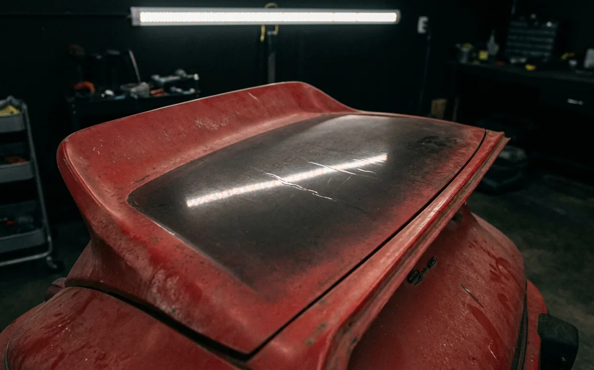 The rear spoiler of a classic red 911, oxidised and chalky